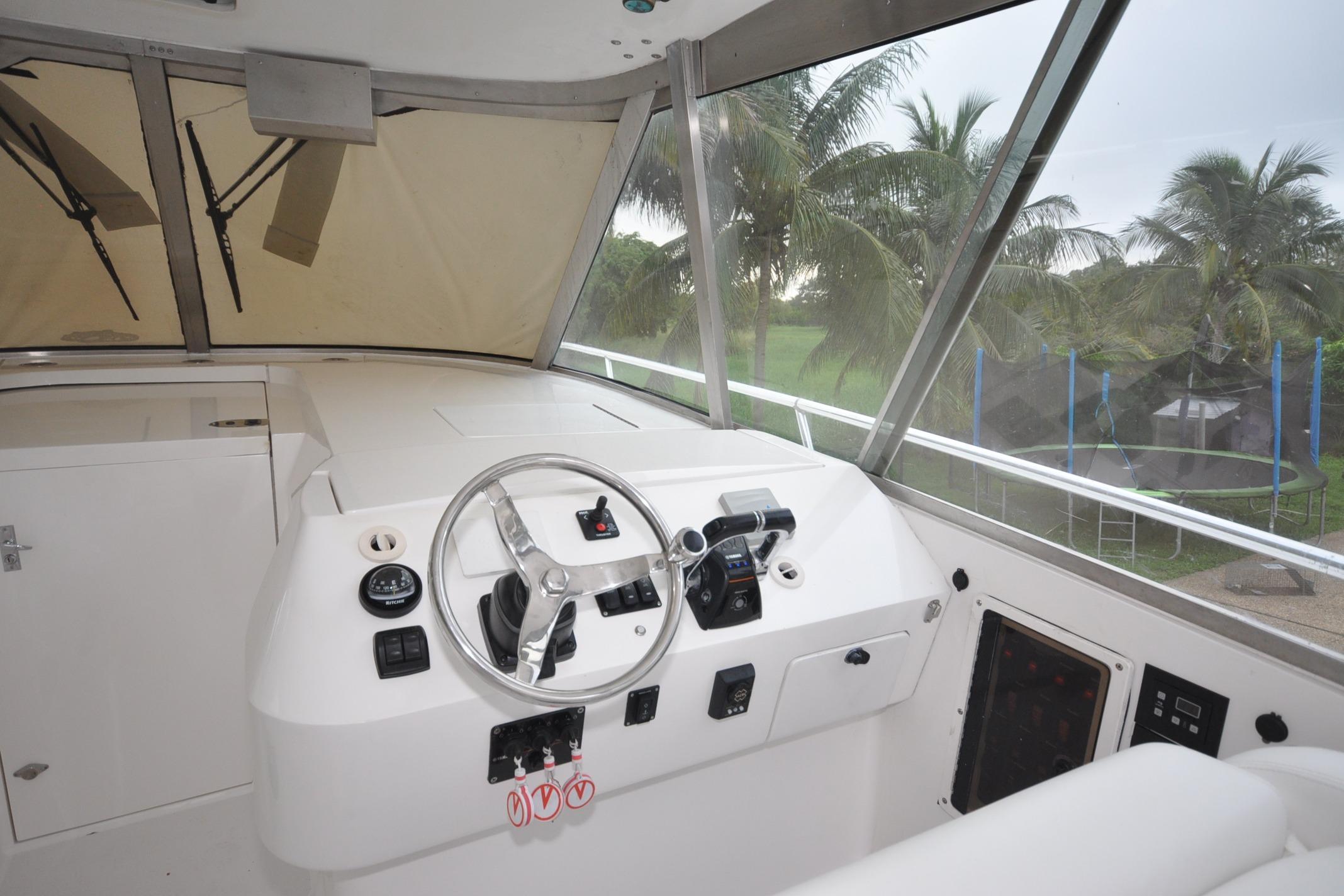 2009 Intrepid 430 Sport Yacht helm with steering wheel and controls, overlooking palm trees.