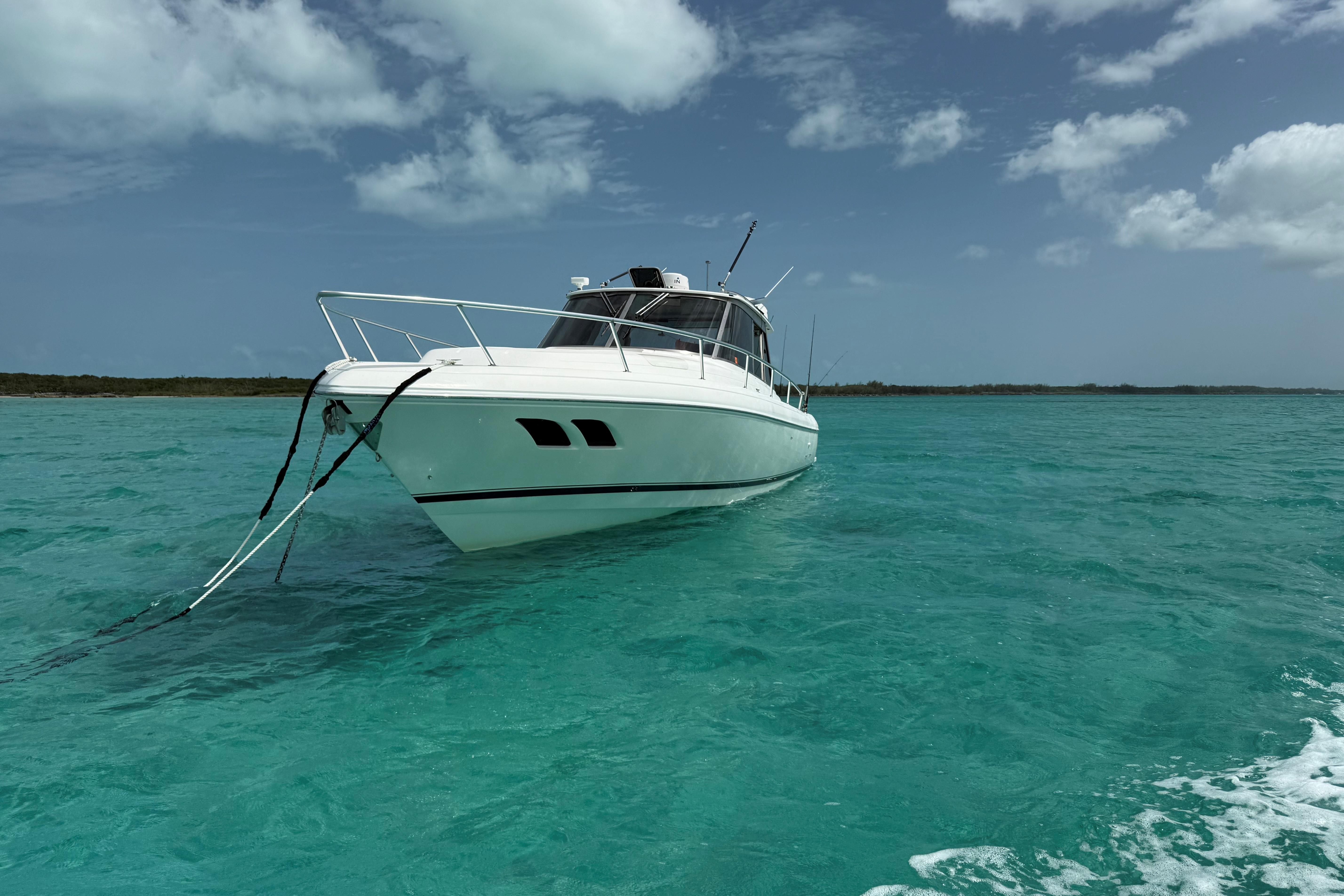 2009 Intrepid 430 Sport Yacht anchored in clear turquoise waters under a partly cloudy sky.