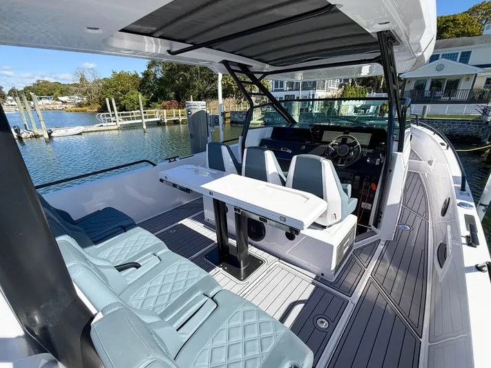  Yacht Photos Pics 2022 Axopar 37 Sun Top boat interior with seating and helm, docked by waterfront homes.