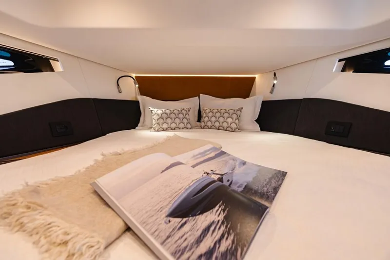  Yacht Photos Pics Luxurious cabin interior of 2024 Azimut Verve 48 yacht with cozy bedding and reading material.