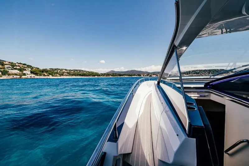  Yacht Photos Pics 2024 Azimut Verve 48 yacht cruising on clear blue waters near a scenic coastline.