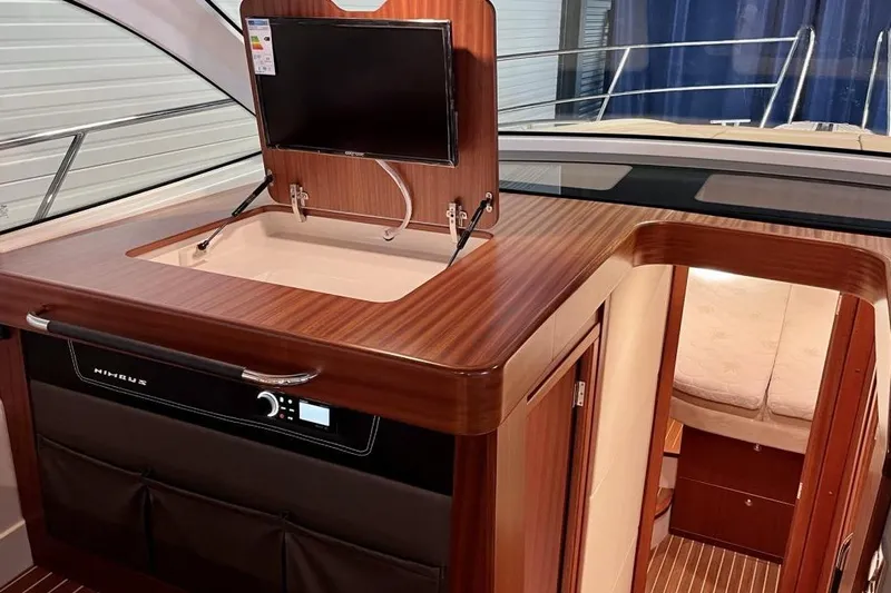  Yacht Photos Pics 2023 Nimbus 405 Flybridge interior with wood finish, TV, and cozy cabin entrance.