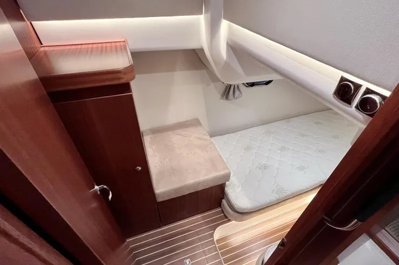  Yacht Photos Pics 2023 Nimbus 405 Flybridge cabin interior with wooden finish and cozy bed.