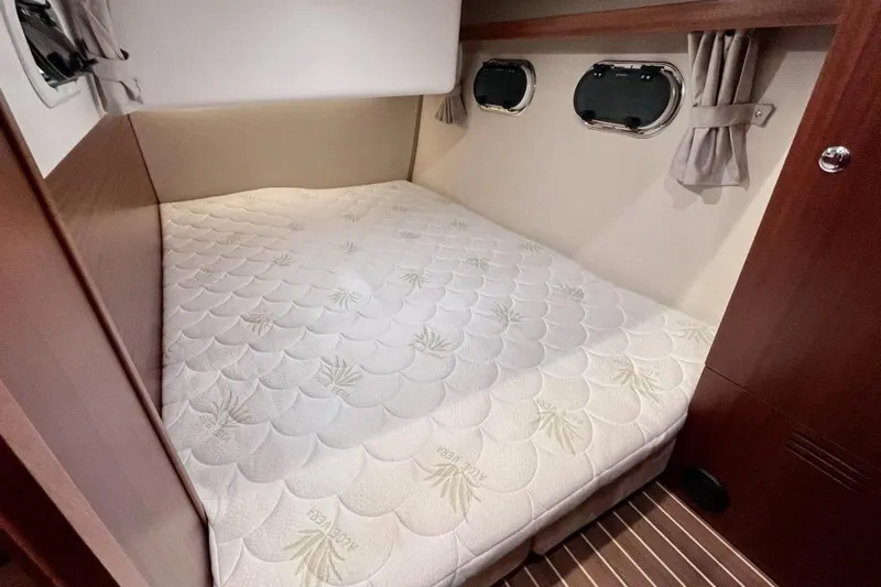  Yacht Photos Pics Luxurious cabin interior of 2023 Nimbus 405 Flybridge with comfortable bed and porthole windows.