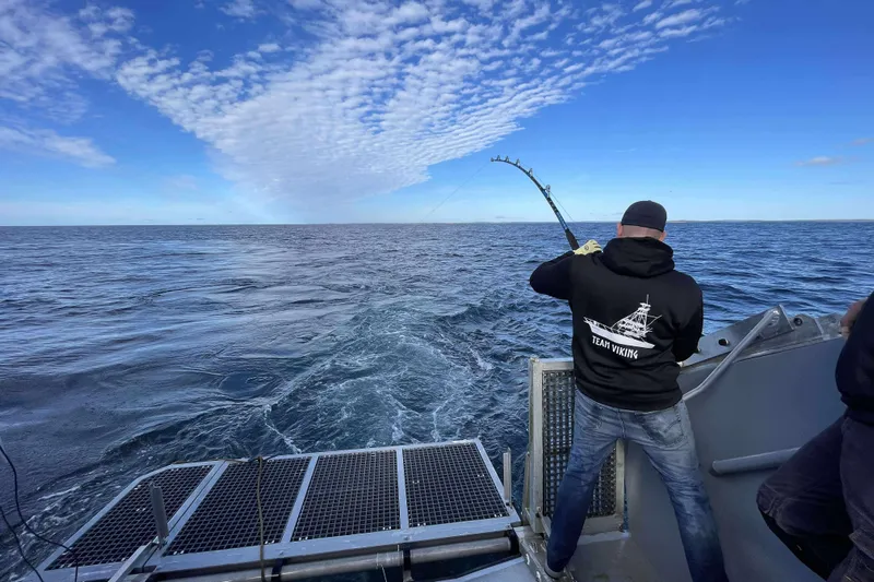 Interceptor Yacht Photos Pics Man fishing on River Hawk 73 Sea Stryker boat under a blue sky.