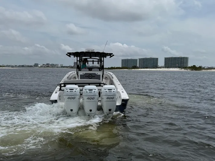  Yacht Photos Pics 2022 Fountain 38TE boat with triple 400 engines cruising on water near shoreline.