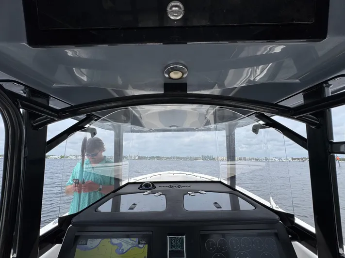  Yacht Photos Pics 2022 Fountain 38TE boat interior with navigation system, person visible outside on water.
