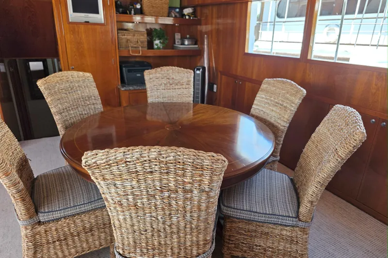 Aspen Afloat Yacht Photos Pics 1974 Chris-Craft Roamer yacht interior with wicker chairs and wooden dining table.