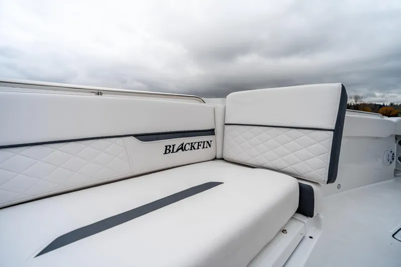 Blackfin 252cc Yacht Photos Pics 2023 Blackfin 252 CC boat with white quilted seating and logo, under cloudy sky.