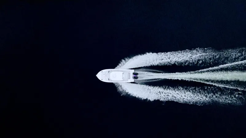 Blackfin 252cc Yacht Photos Pics Aerial view of 2023 Blackfin 252 CC boat creating wake on dark water.