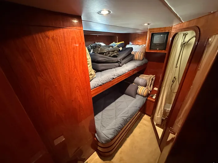 Euphoria Yacht Photos Pics Cozy cabin with wooden interior, bunk beds, and a small TV on a 2001 Johnson 70 yacht.
