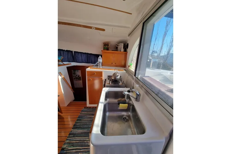 Lagoon 380 Yacht Photos Pics Interior of 2002 Lagoon 380 catamaran kitchen with sink, window, and wooden cabinetry.
