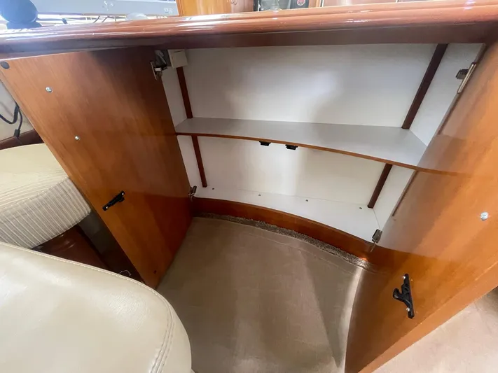 Rudee's Ruckus Yacht Photos Pics Open cabinet inside 2006 Carver 46 Motor Yacht, featuring wooden finish and shelving.