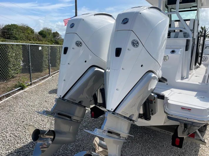 Med Blue Yacht Photos Pics 2025 Blackfin 272CC boat with dual outboard engines, parked on gravel.