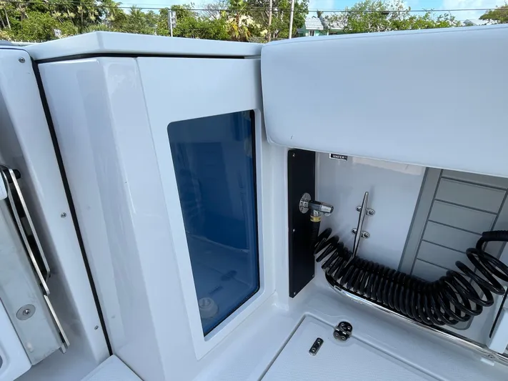 Med Blue Yacht Photos Pics 2025 Blackfin 272CC boat interior with storage compartment and coiled hose.