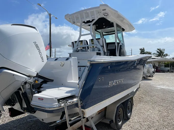 Med Blue Yacht Photos Pics 2025 Blackfin 272CC boat with Mercury engine, parked on a trailer under a clear sky.