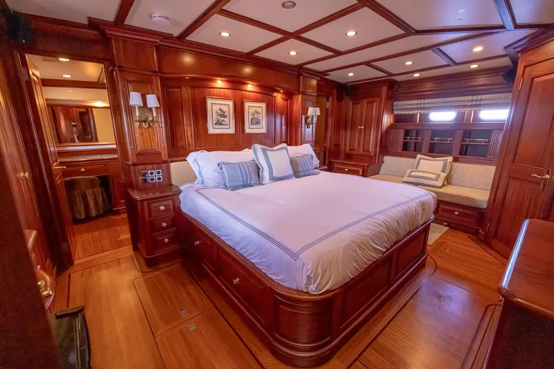Essence Yacht Photos Pics Luxurious wood-paneled bedroom in 2006 Vicem 85 Classic yacht, featuring elegant bedding and cozy seating.