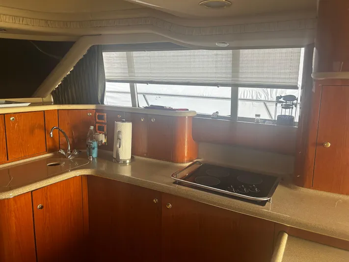Another Chapter Yacht Photos Pics Interior of 1999 Sea Ray 480 Sedan Bridge yacht kitchen with wooden cabinets and stove.
