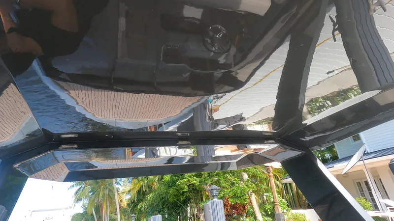 Rand Leisure 28 Yacht Photos Pics Sleek black Rand Leisure 2021 boat with reflective surfaces, docked near tropical greenery.