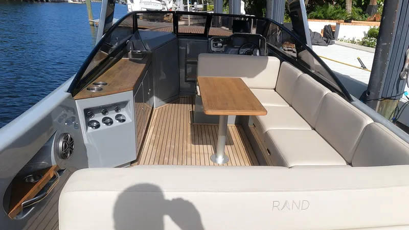 Rand Leisure 28 Yacht Photos Pics 2021 Rand Leisure boat interior with seating, table, and control panel by the water.