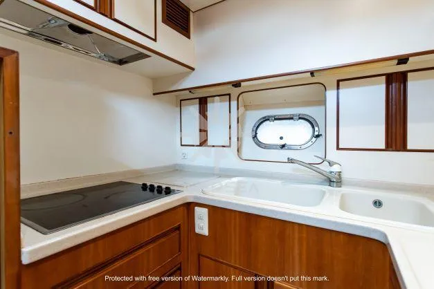 2002 Vitech 58 yacht kitchen with stove, sink, and porthole window.