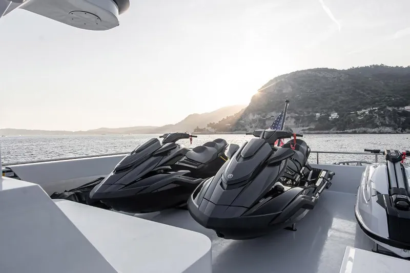 Crossover 27 #1 Yacht Photos Pics 2024 Lynx Crossover 27 jet skis on yacht deck at sunset, coastal backdrop.