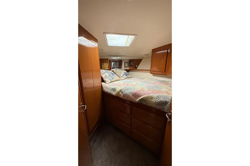 Yacht Photos Pics 1999 Viking 50 Convertible yacht bedroom with wood cabinets and colorful bedding.