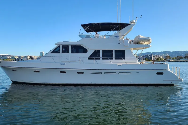 Yachtmaster Yacht Photos Pics Luxury 2002 Symbol 58 yacht on calm water, clear blue sky background.