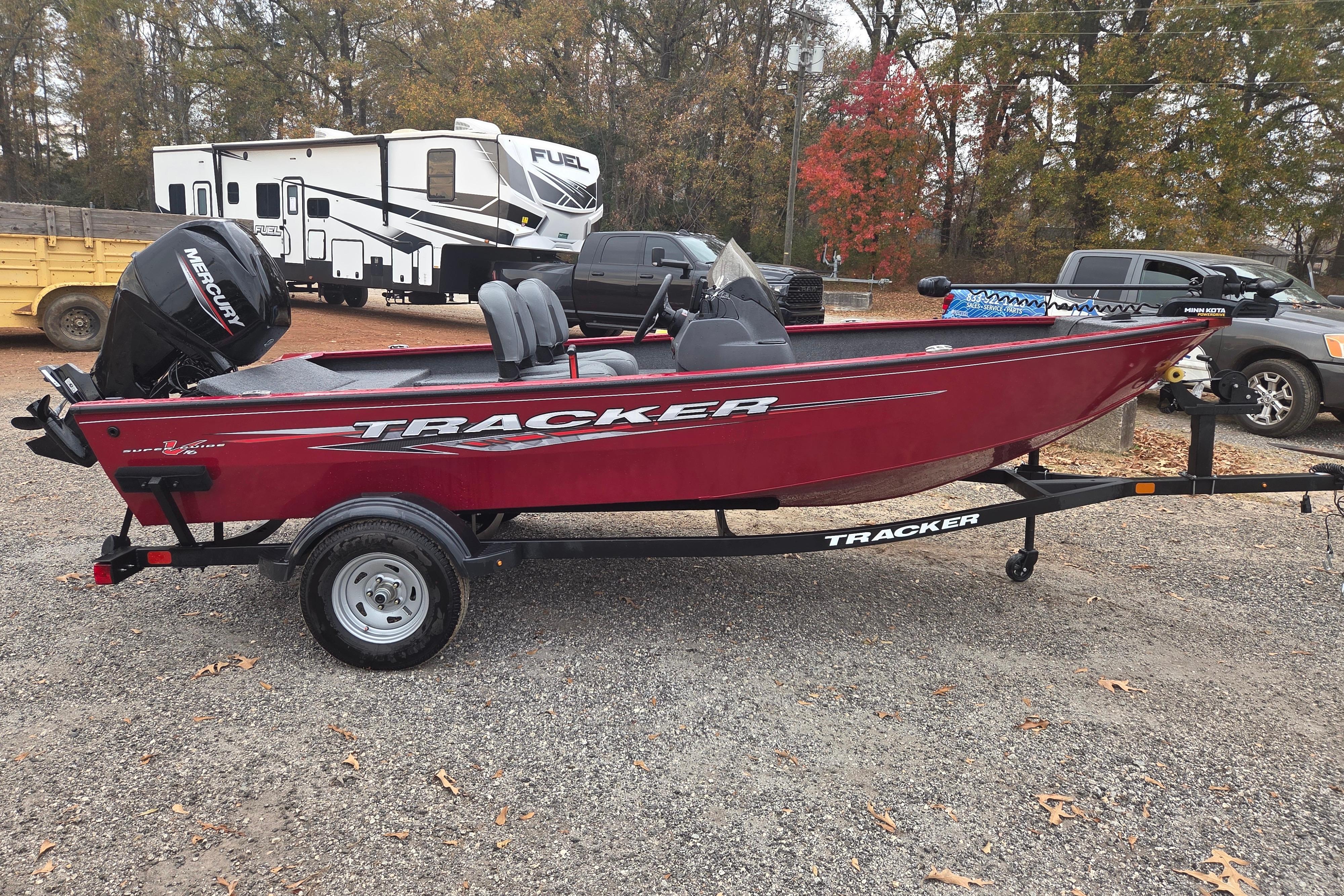 2025 Tracker Super Guide V-16 SC boat on trailer, parked outdoors.