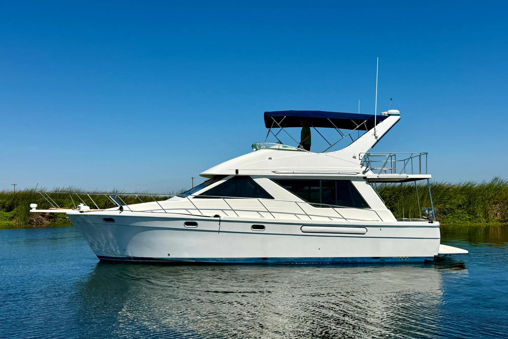 1998 Bayliner 3988 Command Bridge Motoryacht on calm water under clear blue sky.