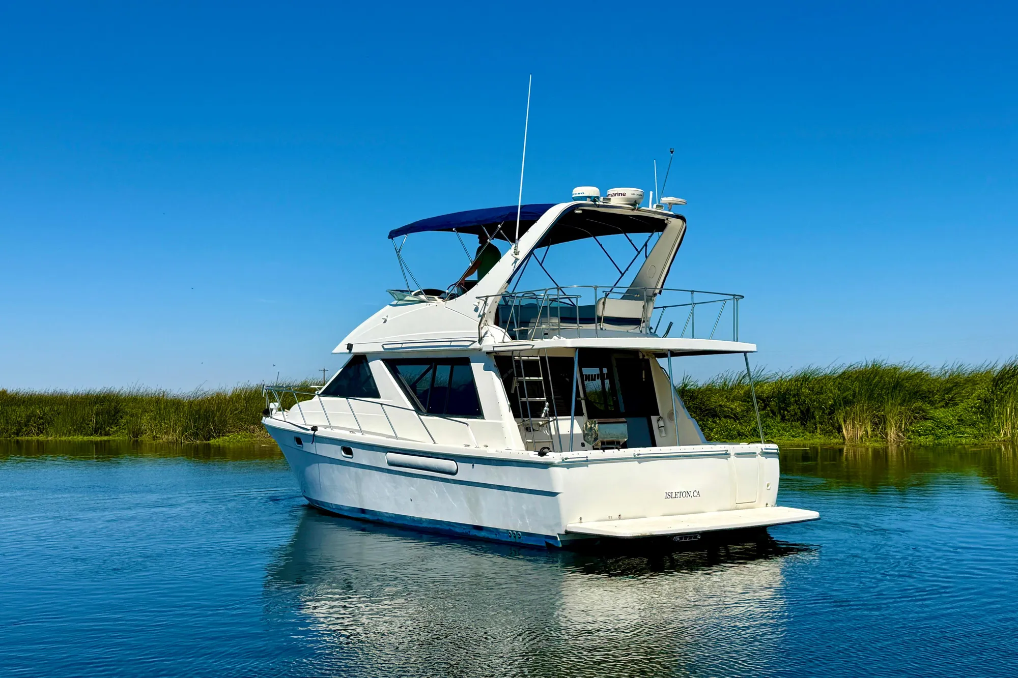 1998 Bayliner 3988 Command Bridge Motoryacht on calm water under clear blue sky.