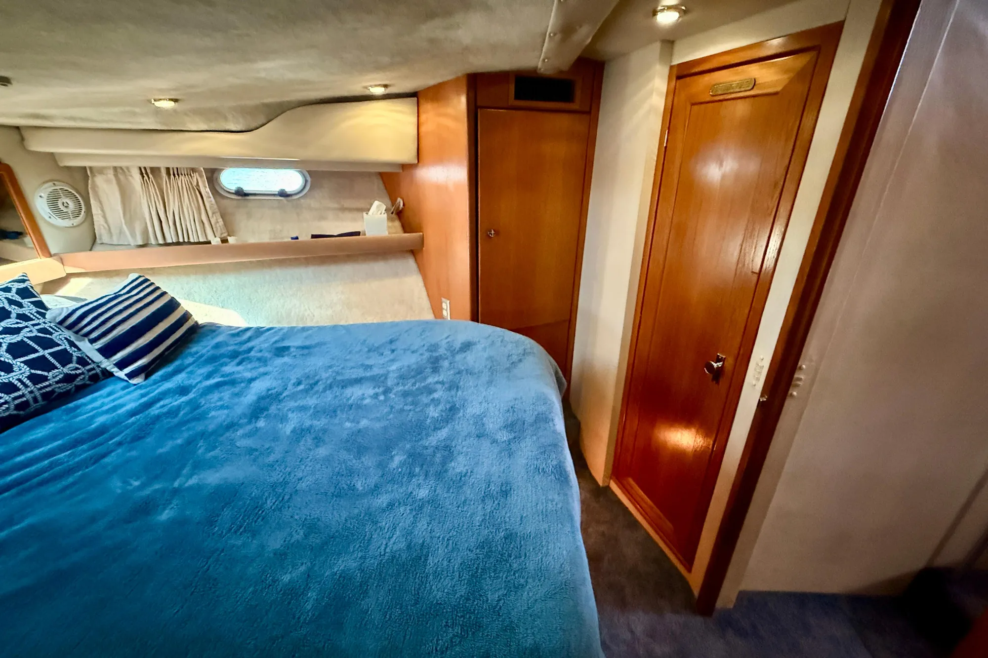 Cozy bedroom in 1998 Bayliner 3988 Command Bridge Motoryacht with blue bedding and wooden accents.