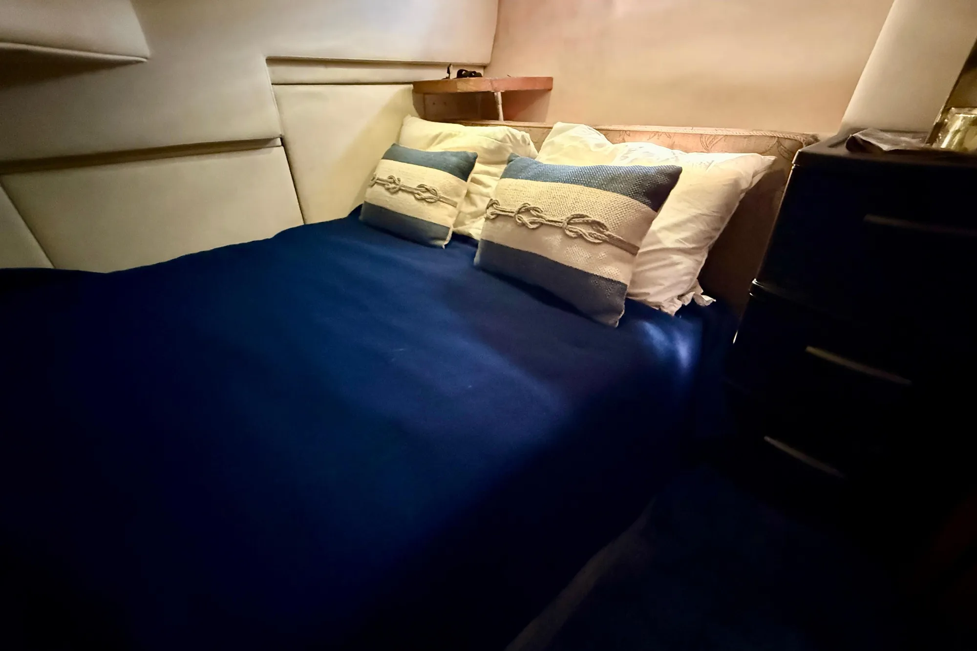Cozy bedroom interior of 1998 Bayliner 3988 Command Bridge Motoryacht with nautical-themed pillows.