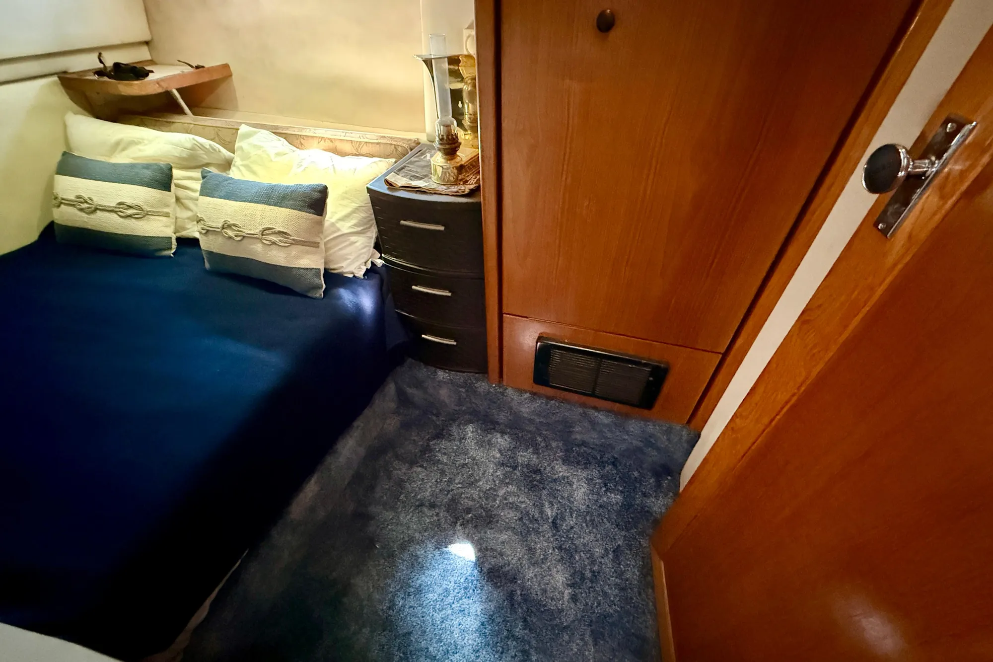 Cozy bedroom in 1998 Bayliner 3988 Command Bridge Motoryacht with blue bedding and wooden cabinetry.