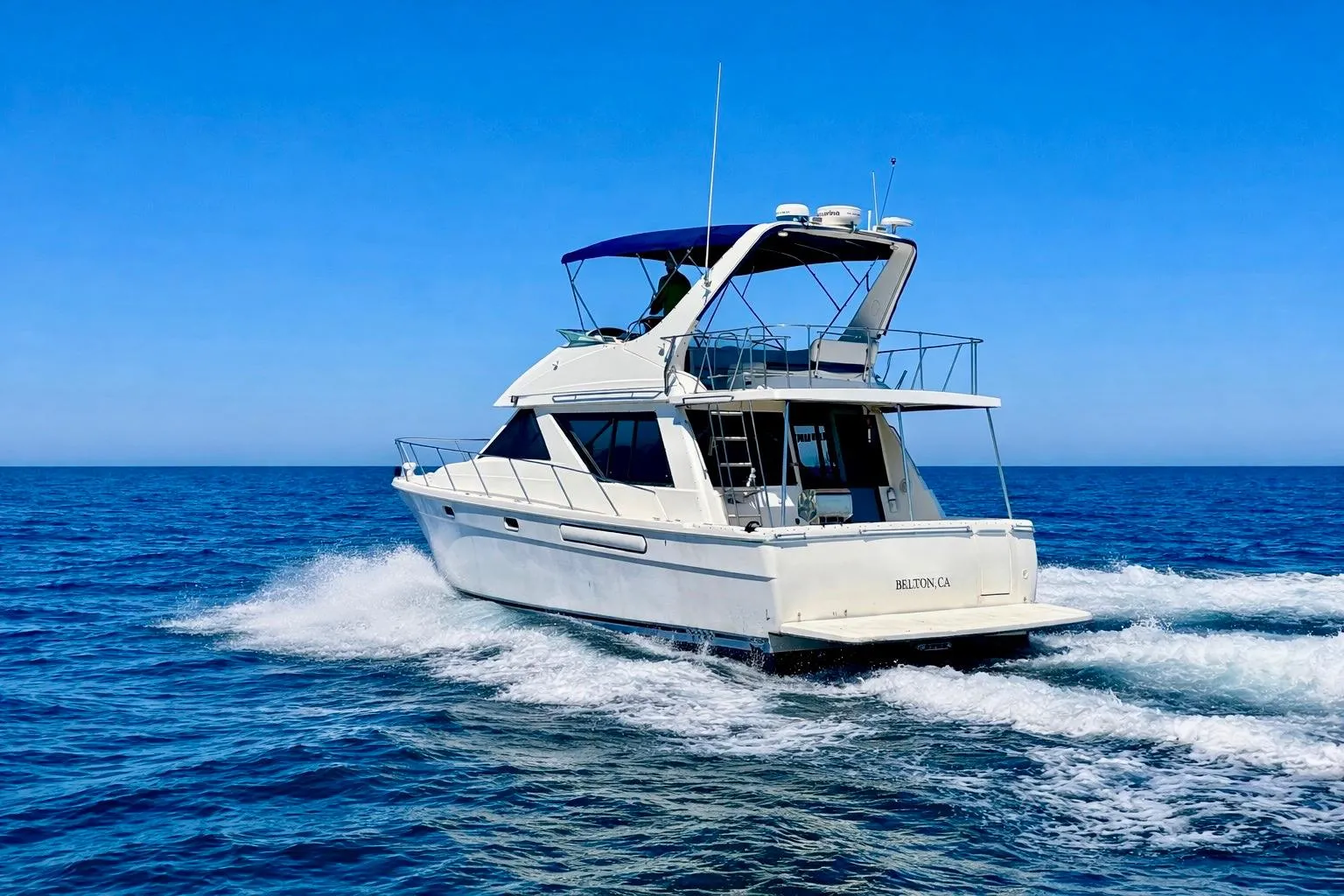 1998 Bayliner 3988 Command Bridge Motoryacht cruising on open sea under clear blue sky.