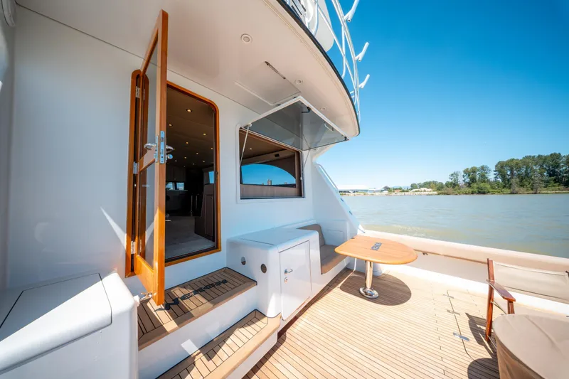  Yacht Photos Pics 1998 Donzi R73 yacht deck with open door, wooden table, and scenic river view.