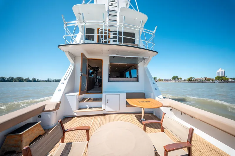  Yacht Photos Pics 1998 Donzi R73 yacht with spacious deck, wooden table, and chairs on a sunny day.