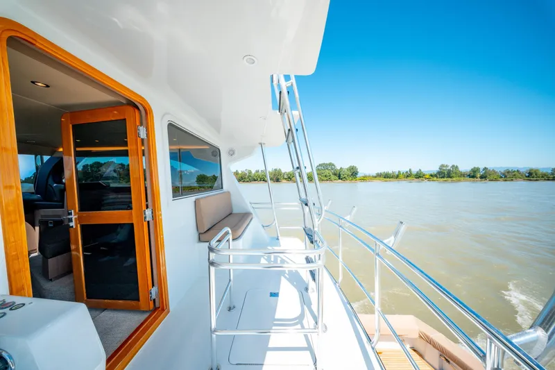  Yacht Photos Pics 1998 Donzi R73 yacht deck with wooden door, overlooking serene water and lush shoreline.