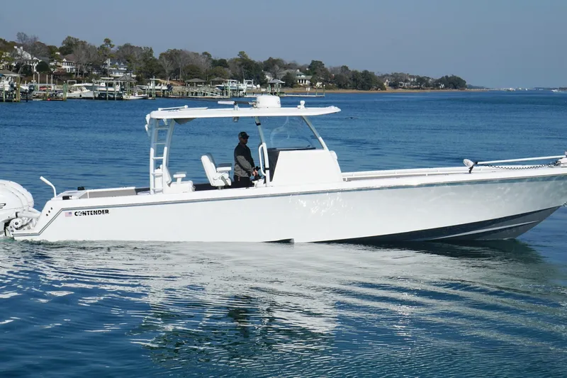  Yacht Photos Pics 2024 Contender 39 ST boat cruising on a calm blue lake near a residential shoreline.