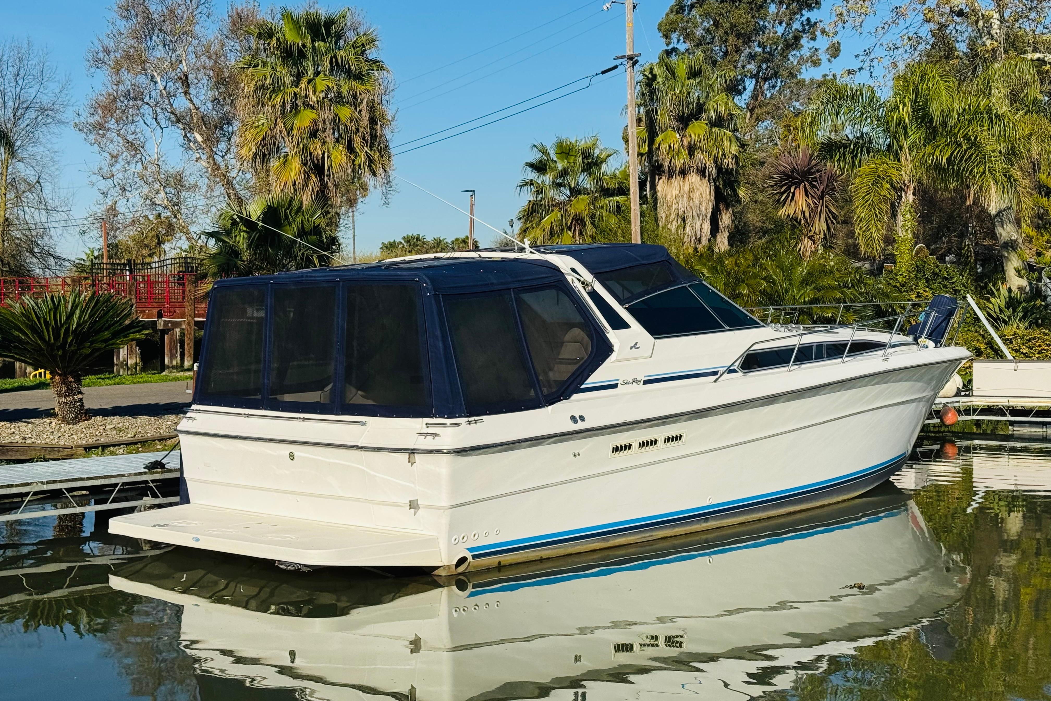 1989 Sea Ray 390 Express Cruiser docked on calm water, surrounded by lush greenery.