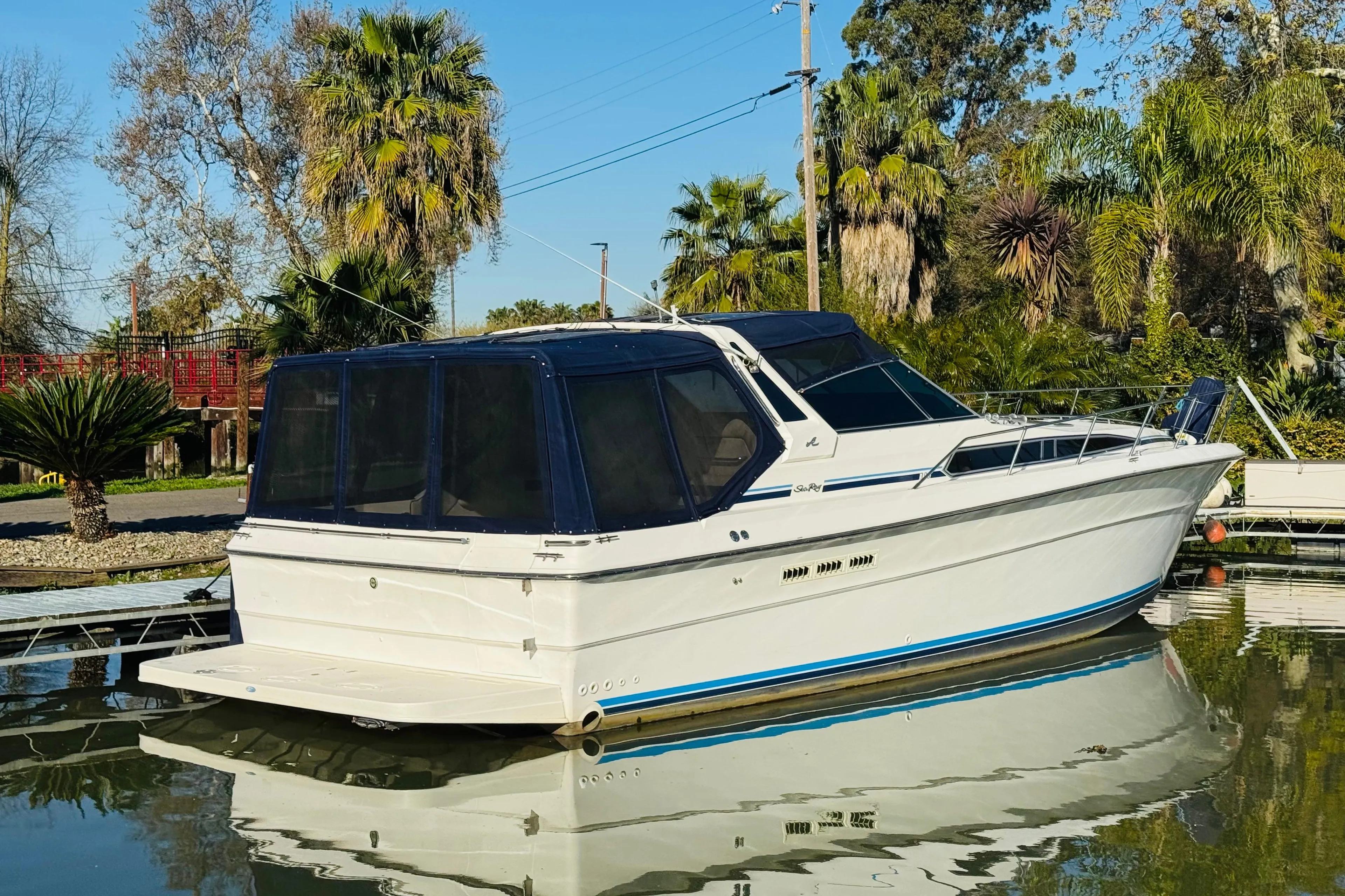 1989 Sea Ray 390 Express Cruiser docked on calm water, surrounded by lush greenery.