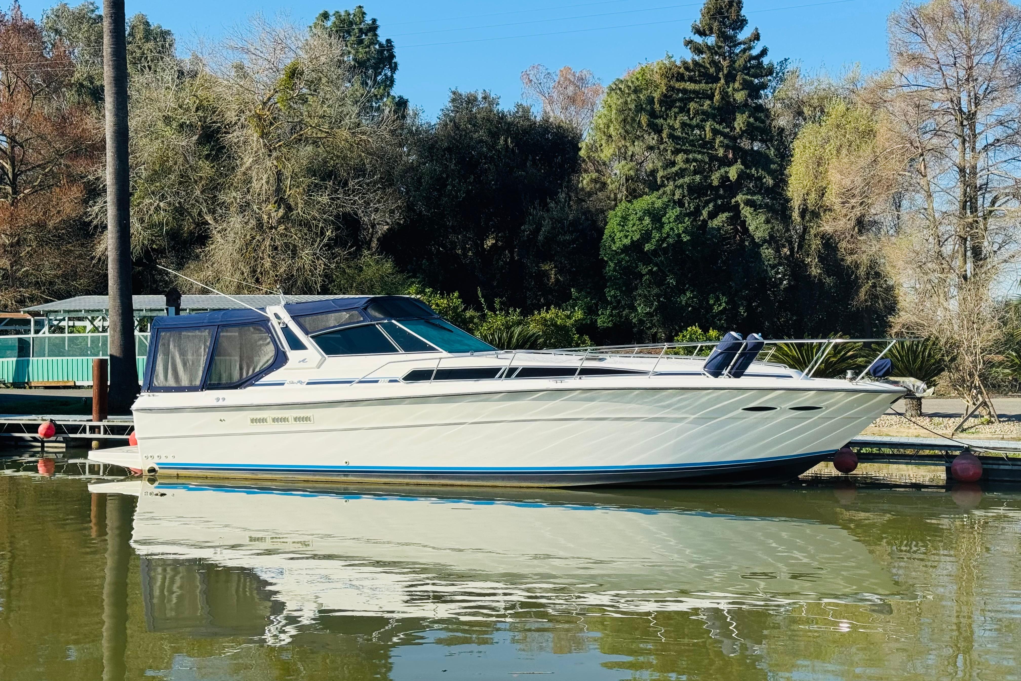 1989 Sea Ray 390 Express Cruiser docked on calm water, surrounded by trees.