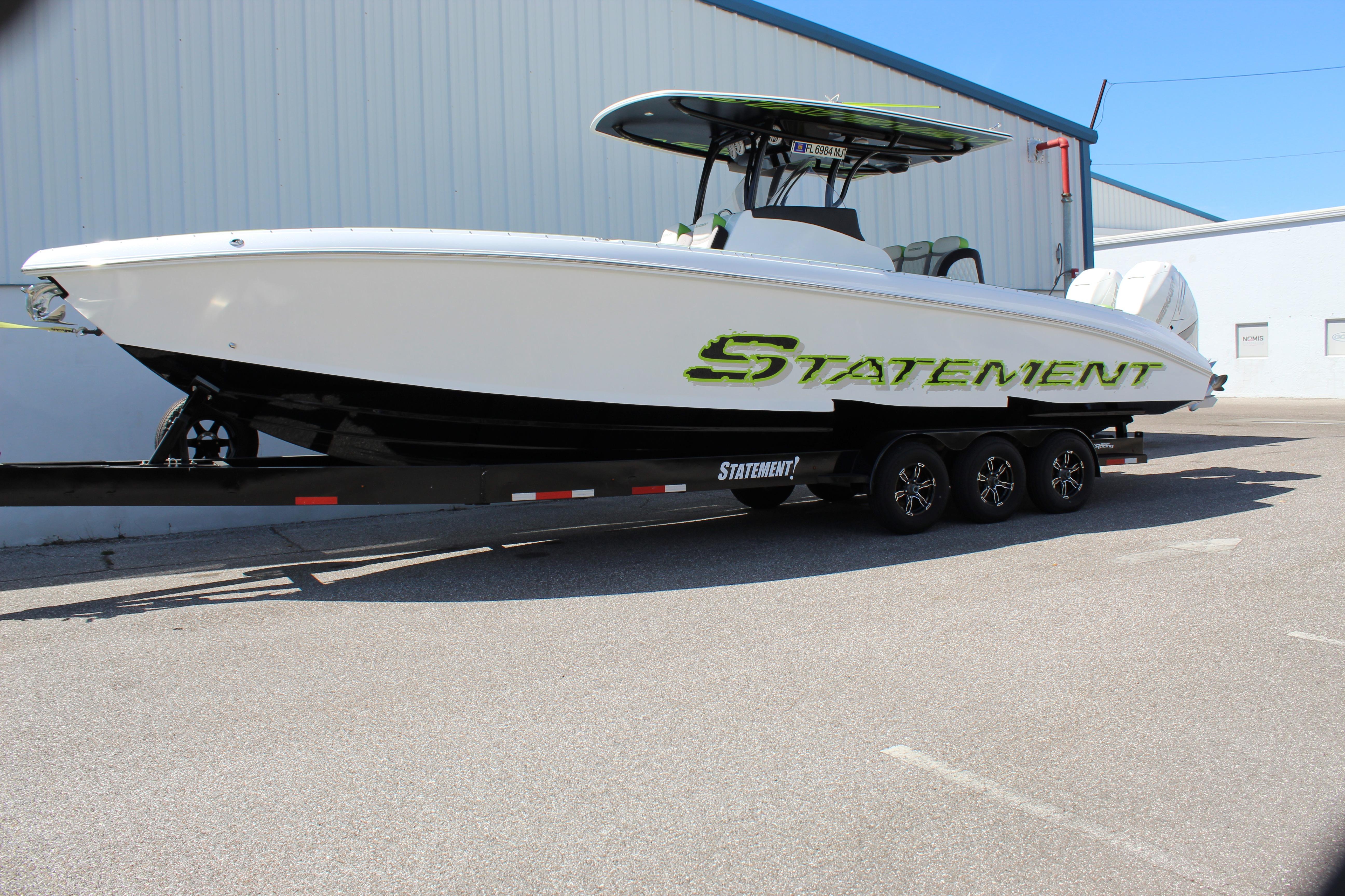 2017 Statement 350 Open boat on trailer, white hull with green logo, parked outdoors.