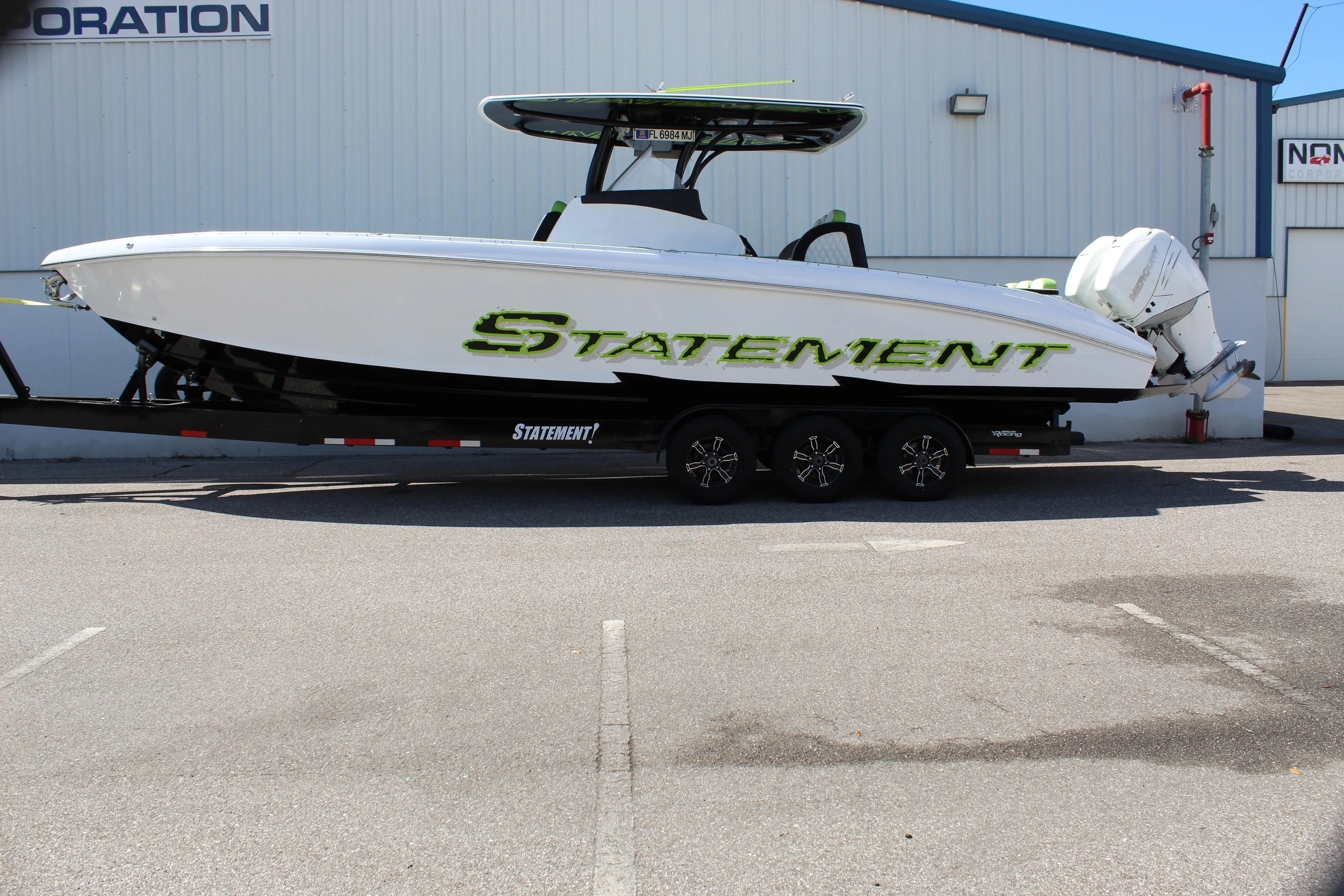 2017 Statement 350 Open boat on trailer, white with green accents, parked outdoors.