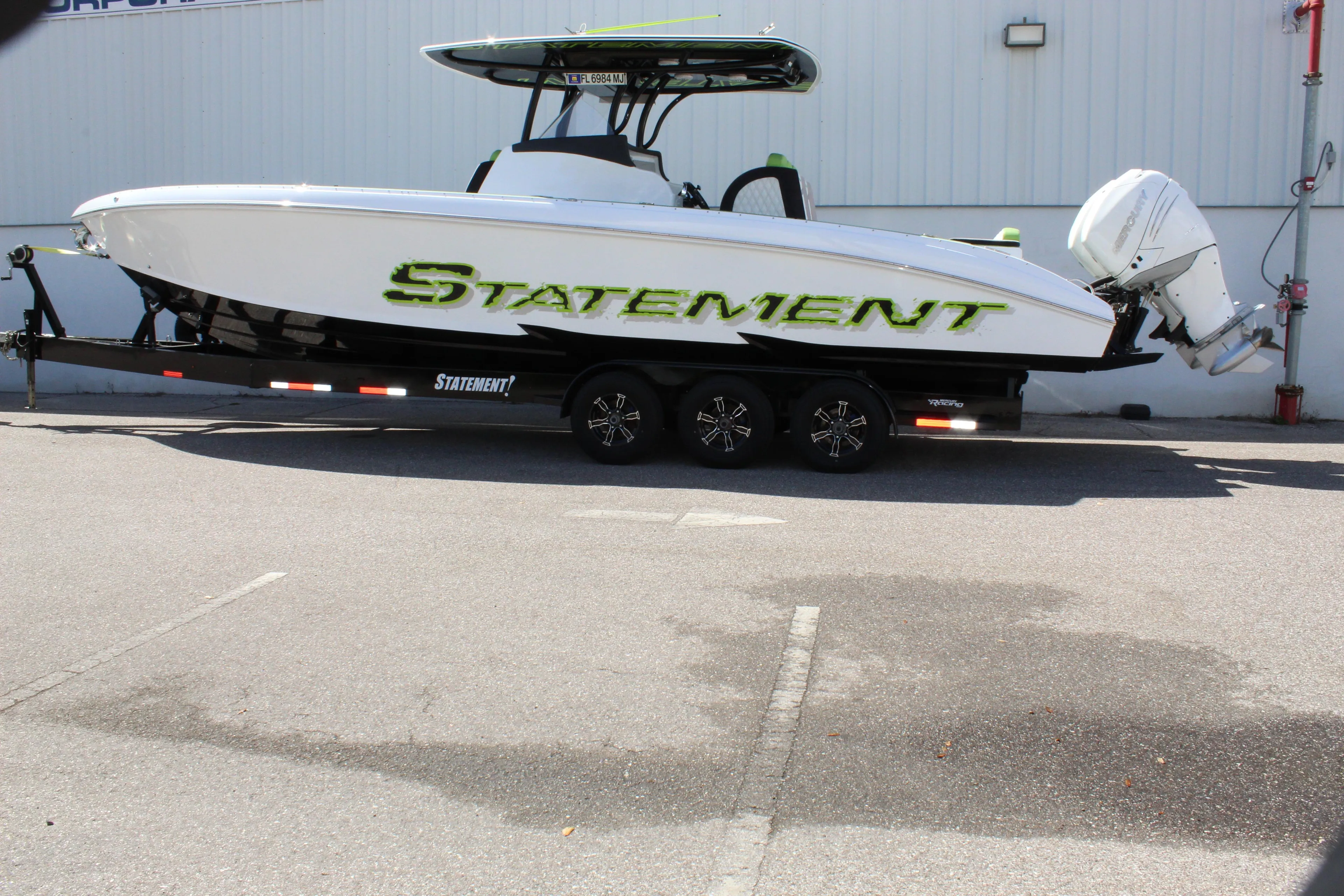 2017 Statement 350 Open boat on trailer, white with green accents, parked outdoors.
