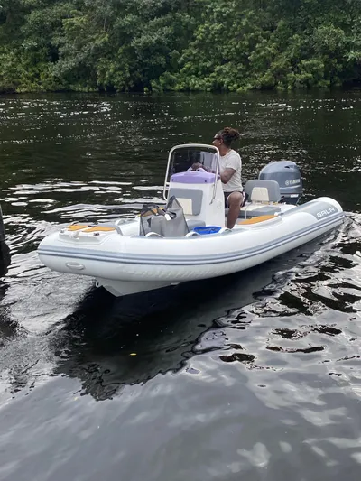 Sue Carolyn Yacht Photos Pics Person on inflatable boat navigating river, surrounded by lush greenery.