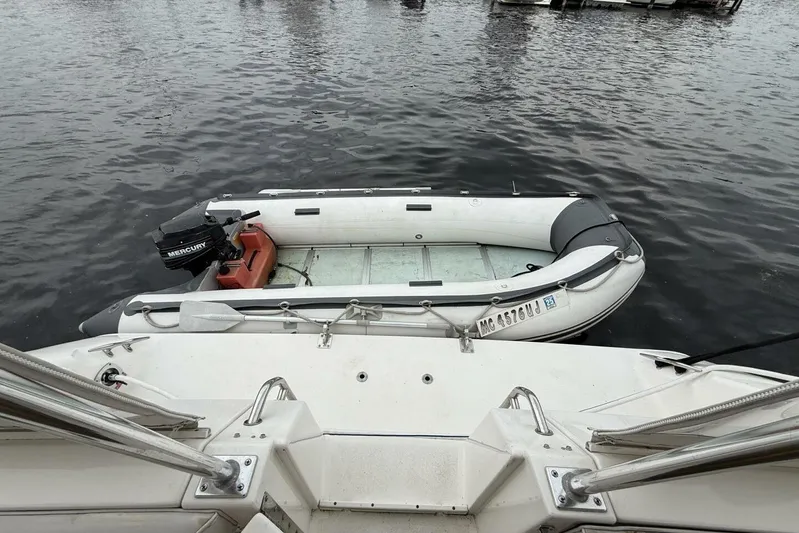  Yacht Photos Pics 1995 Sea Ray 550 Sedan Bridge with inflatable dinghy and Mercury outboard motor on water.