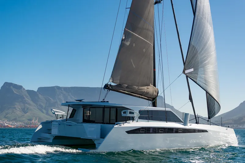  Yacht Photos Pics Ocean Renegade R6 2025 catamaran sailing on the ocean with mountains in the background.