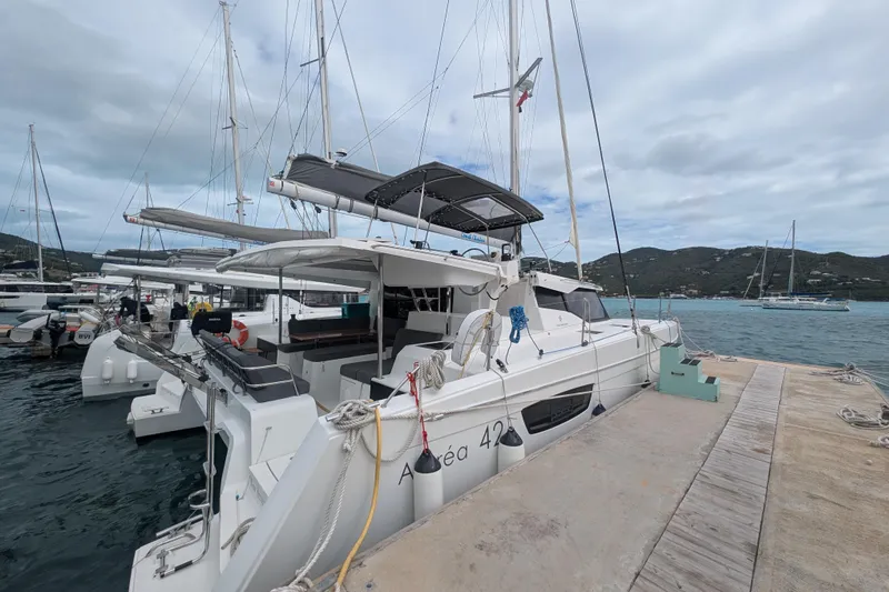 Maho Yacht Photos Pics 2021 Fountaine Pajot Astrea 42 Catamaran docked at marina, cloudy sky, scenic background.