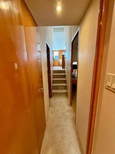  Yacht Photos Pics Hallway inside 2002 Hatteras 55 Convertible yacht, featuring wooden doors and carpeted stairs.